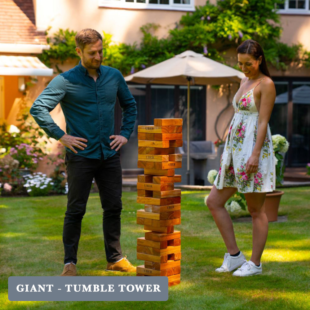 Two adults playing a game of XXL Jenga in a garden while smiling