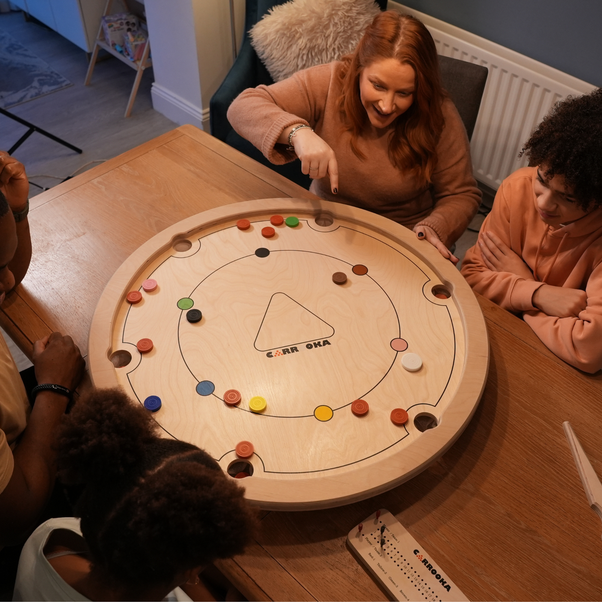 Familie spielt Carrooka Natural am Esstisch, von oben gesehen