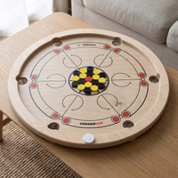 Carrooka Carrom360 Drehbrett auf einem Couchtisch, mit gelben und schwarzen Spielsteinen in der Mitte und weißem Striker