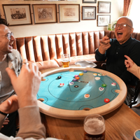 Freunde lachen bei einer Partie Carrooka Pool 8 Blue an einem Tisch im Pub